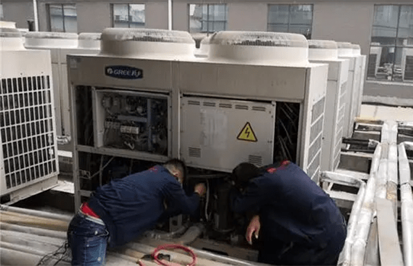 two technicians are repairing the heat pump units